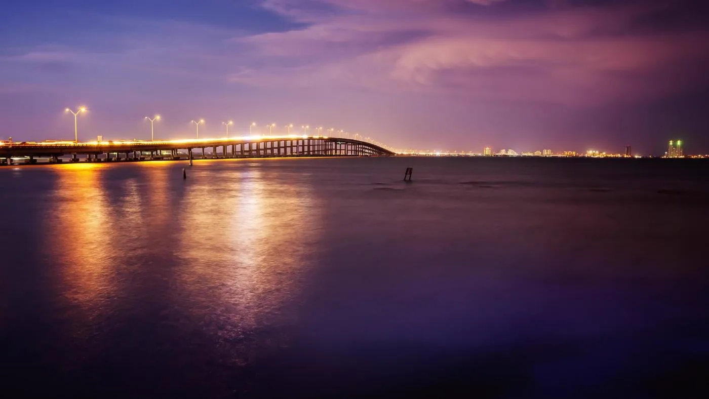 The Queen Isabella Causeway lit at dusk, seen across the Laguna Madre.